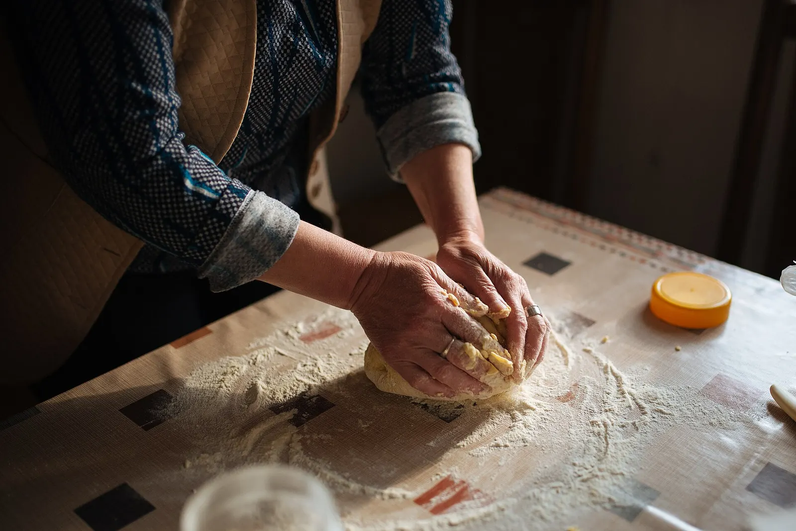 Hands kneading bread dough on a floured table